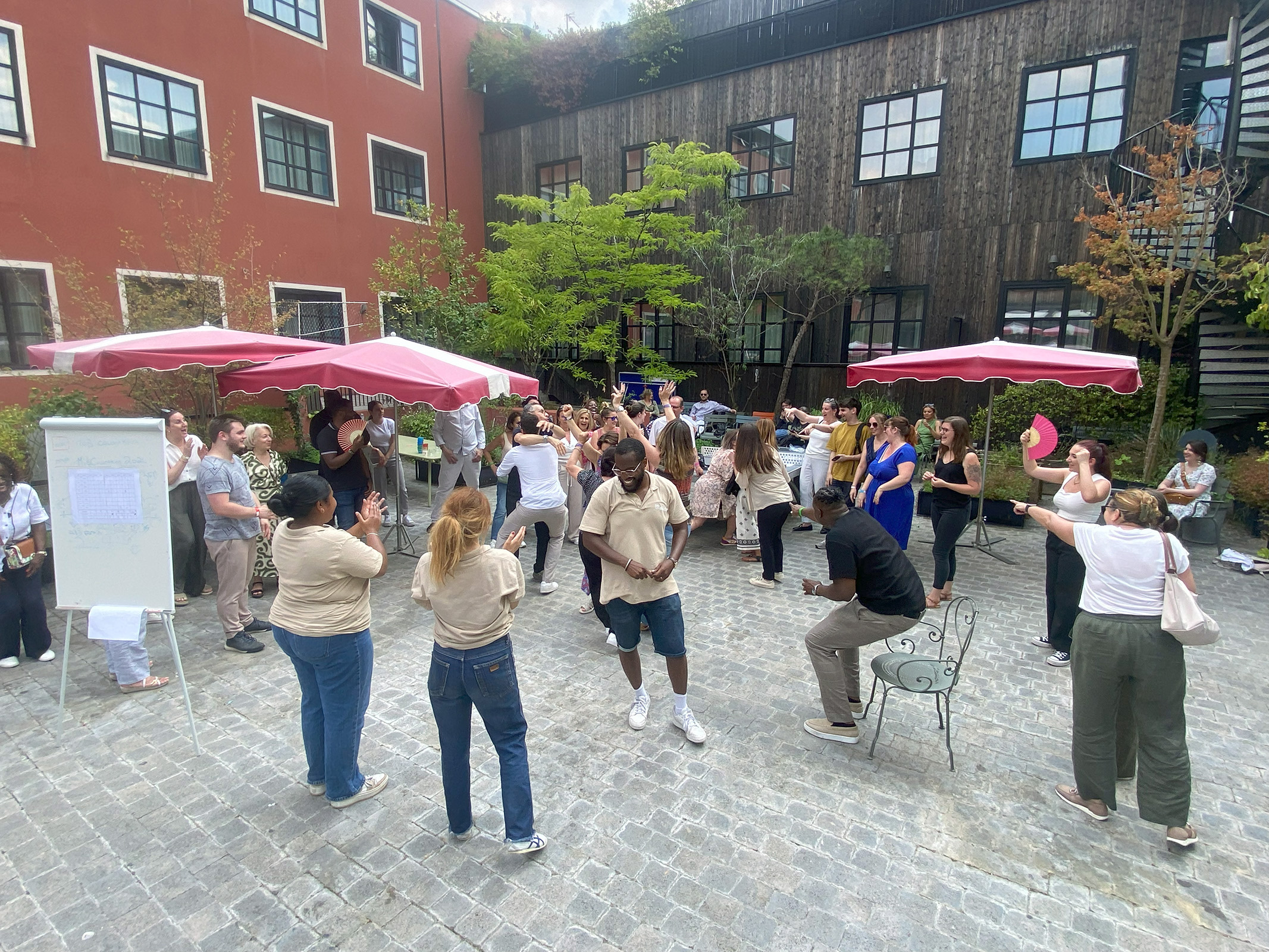 Équipe d'entreprise en plein air lors d'une animation Olympiades, participants répartis en groupes autour d'épreuves de défis collaboratifs sur pelouse