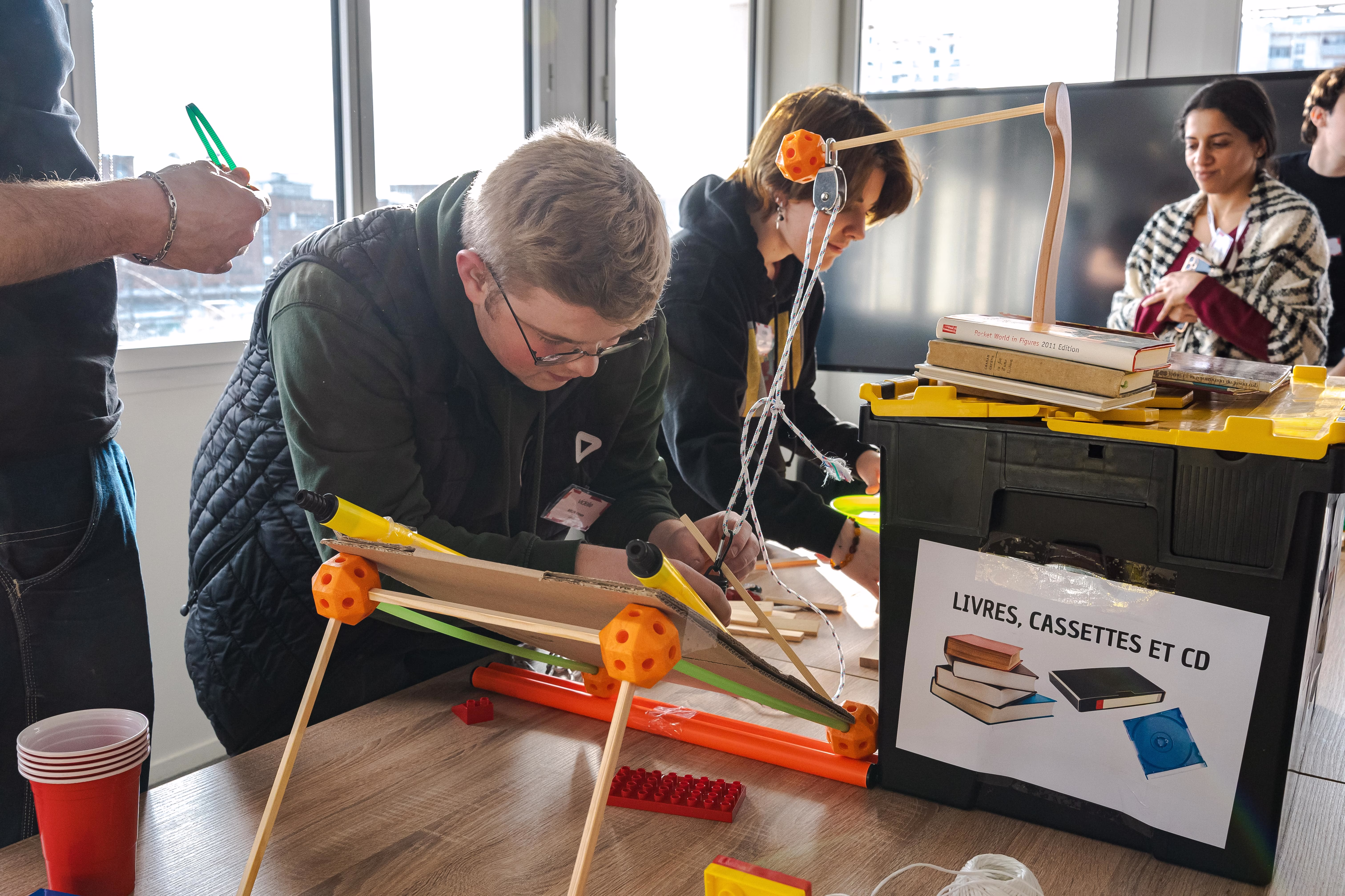 Équipe d'entreprise autour d'un parcours mécanique Réaction en chaîne, collaborateurs en pleine construction collective lors d'un team building animé par Yaazzz