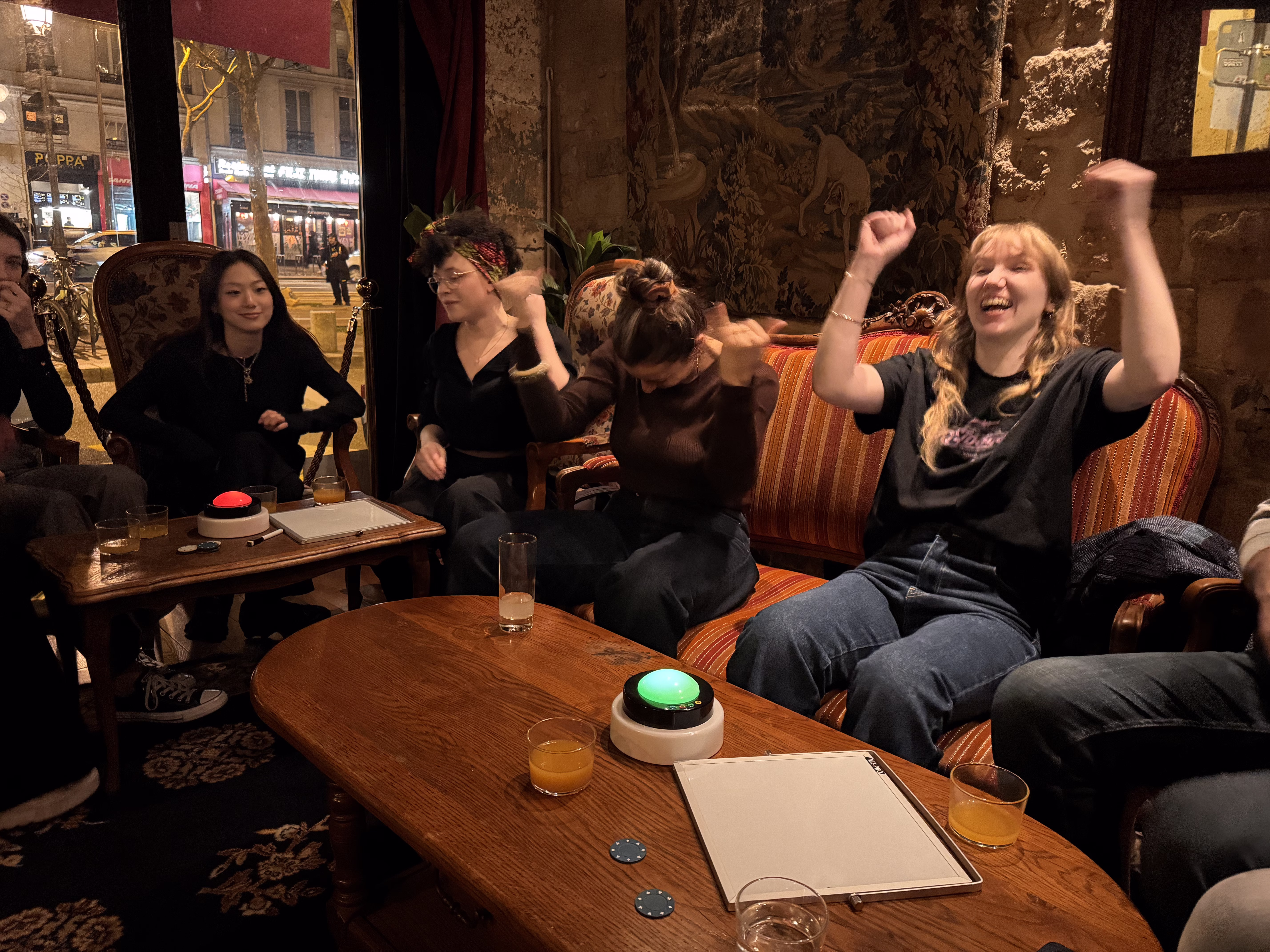 Groupe de collaborateurs en pleine session de blind test en entreprise, buzzers sur la table, ambiance de soirée festive