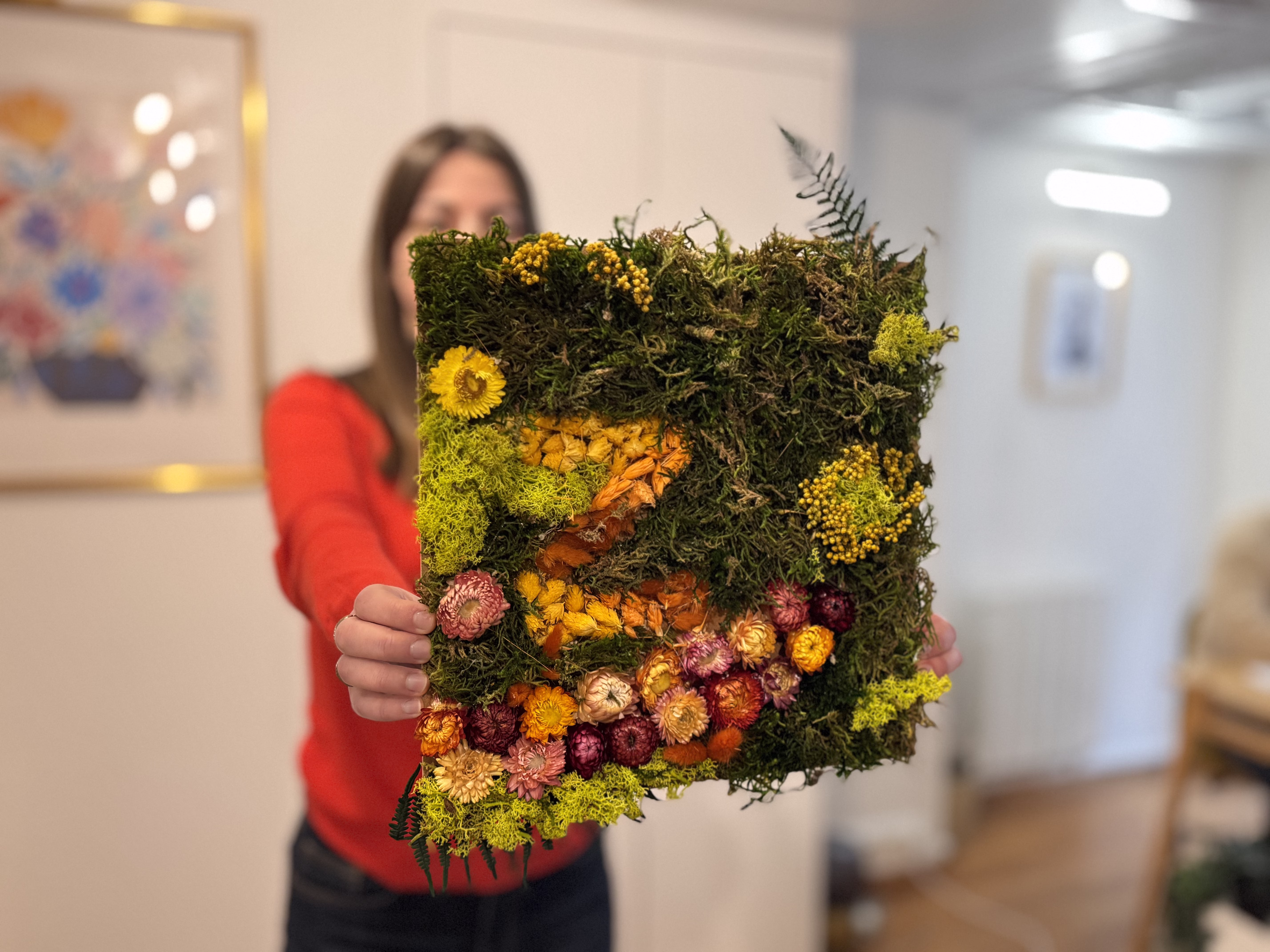 Participants d'un atelier Puzzle Végétal en entreprise, chacun composant sa pièce avec mousses et fleurs séchées, ambiance calme et appliquée
