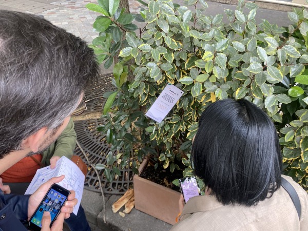Participants d'une session de geocaching team building en extérieur, cartes en main, en train de chercher une balise cachée dans un espace vert urbain